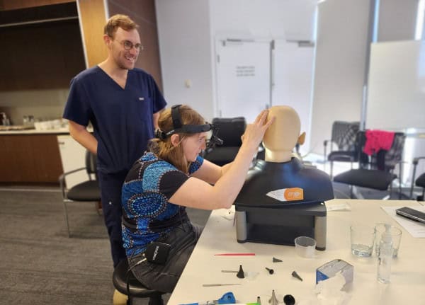 A doctor and clinician engaging in hands-on training for ear and hearing devices in a medical clinic.